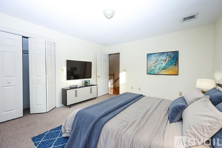 A bedroom with a bed, a television, and a painting on the wall.