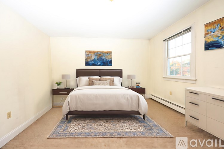A bedroom with a large bed, a rug, and a painting on the wall.