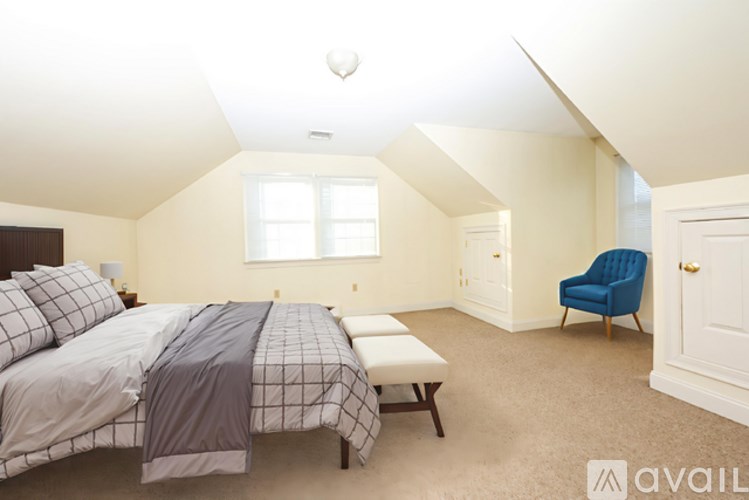 A bedroom with a bed, chair, and window.