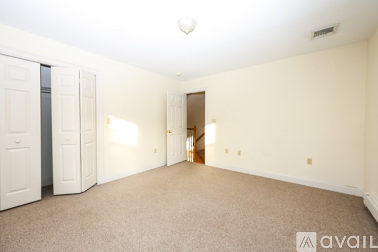 A spacious room with beige carpeting and white walls.