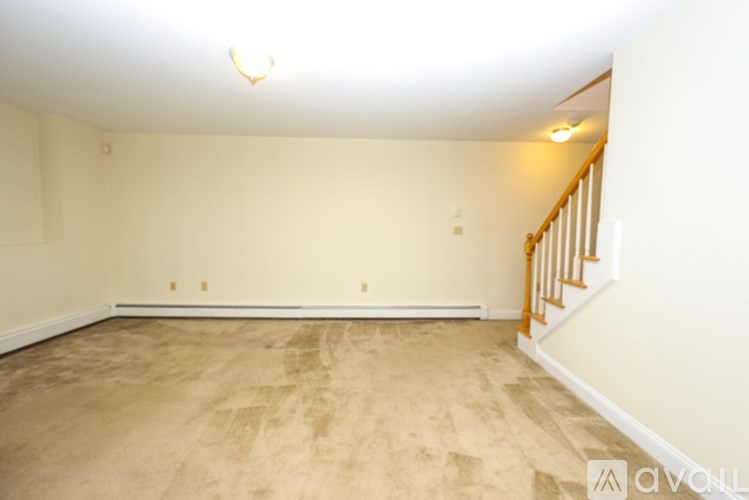 A room with a carpeted floor and a staircase.