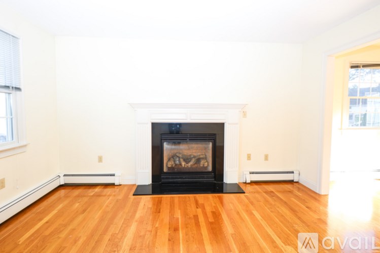 A living room with a fireplace and wooden floors.