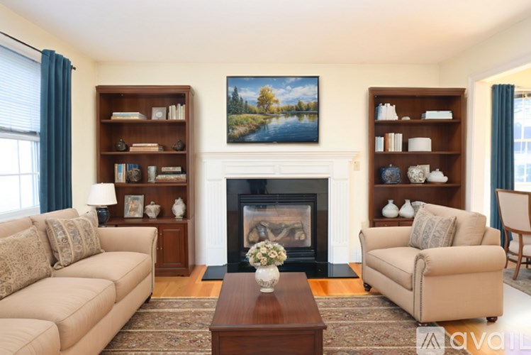 A living room with a fireplace, two couches, and a painting on the wall.