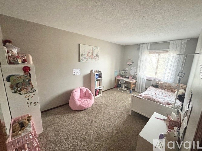 A bedroom with a bed, chair, and a refrigerator with magnets and pictures.