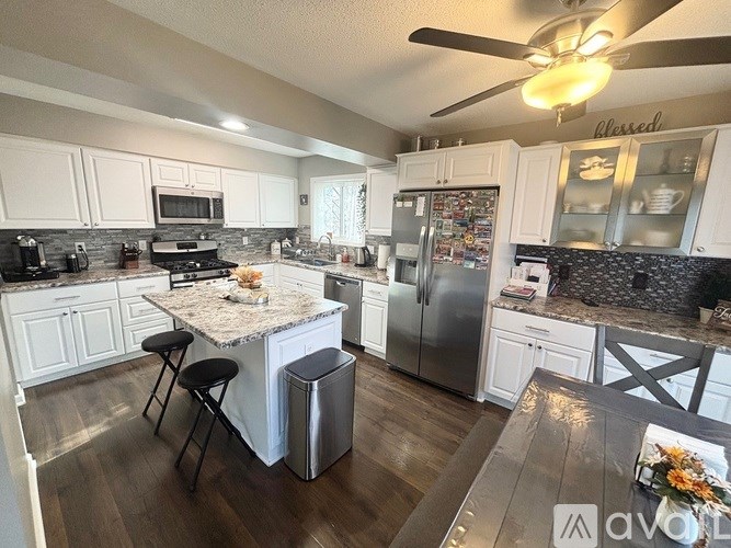 A kitchen with a granite island and a refrigerator covered in magnets.