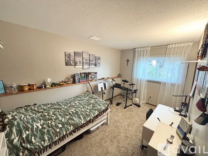 A bedroom with a bed, desk, and musical equipment.