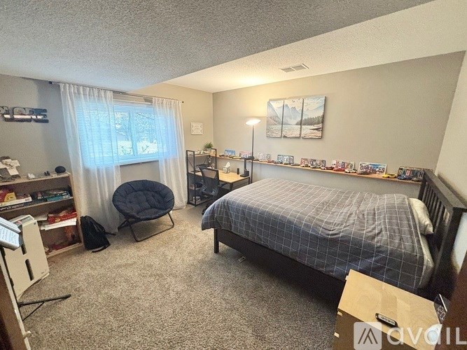 A bedroom with a bed, chair, and a window with curtains.