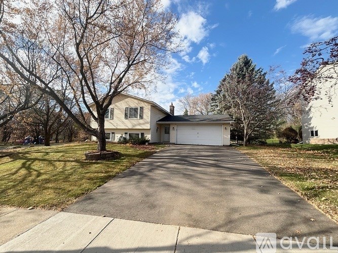A house with a driveway and a tree in front.