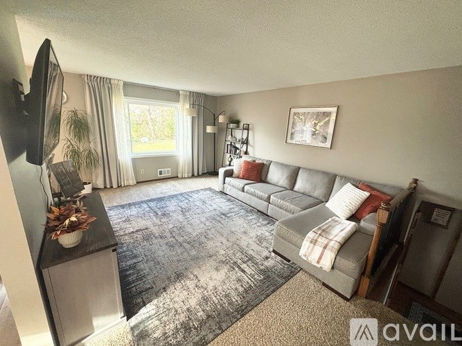 A living room with a grey sofa and a television on the left side.