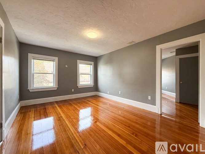 A room with wooden floors and two windows.