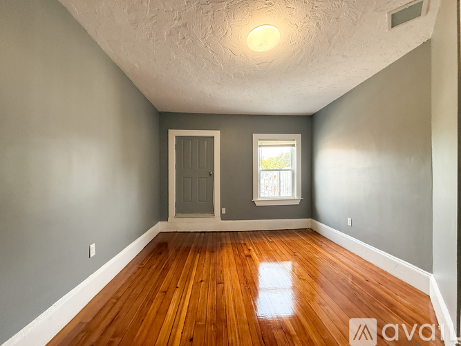 A room with wooden floors and a window with a view of trees.