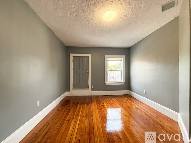 A room with wooden floors and a window with a view of trees.