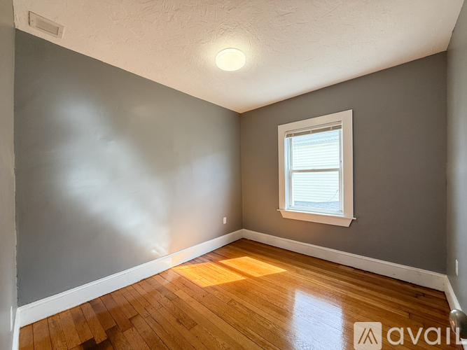 A room with a window and wooden flooring.