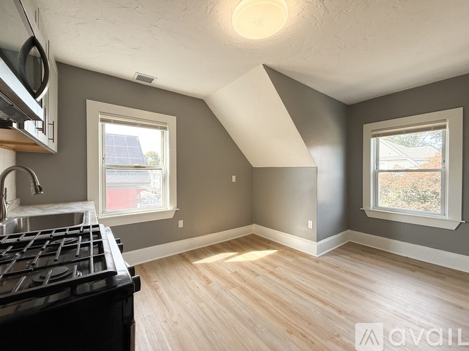 A kitchen with a black stove top oven and a window with a view of a red building.