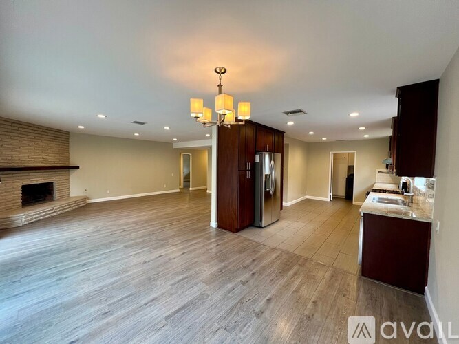 A spacious living room with wood flooring and a chandelier.
