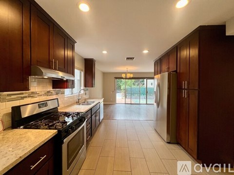 A kitchen with dark wood cabinets and a marble countertop.