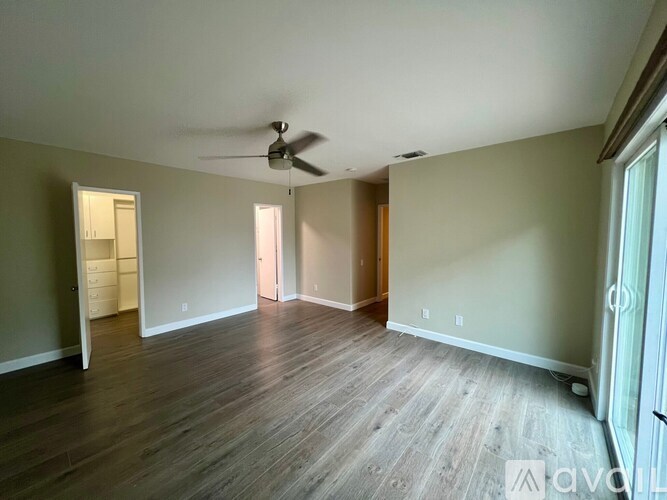 A room with a ceiling fan and wooden flooring.
