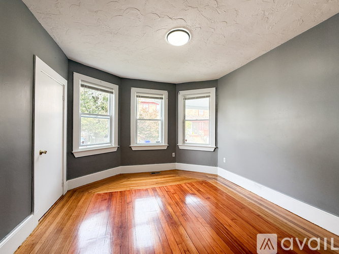 A room with wooden floors and three windows.