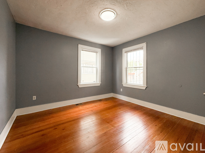 A room with wooden floors and two windows.