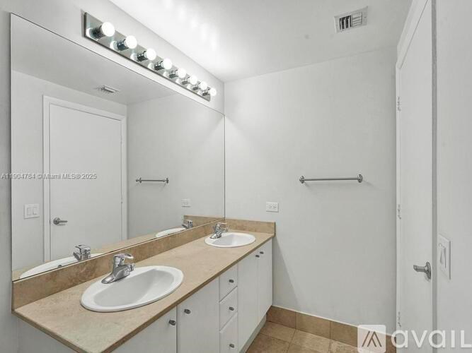 A bathroom with a vanity, two sinks, and a mirror.
