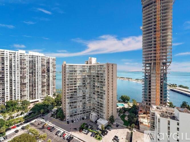 A view of a city with a large building in the foreground and a body of water in the background.
