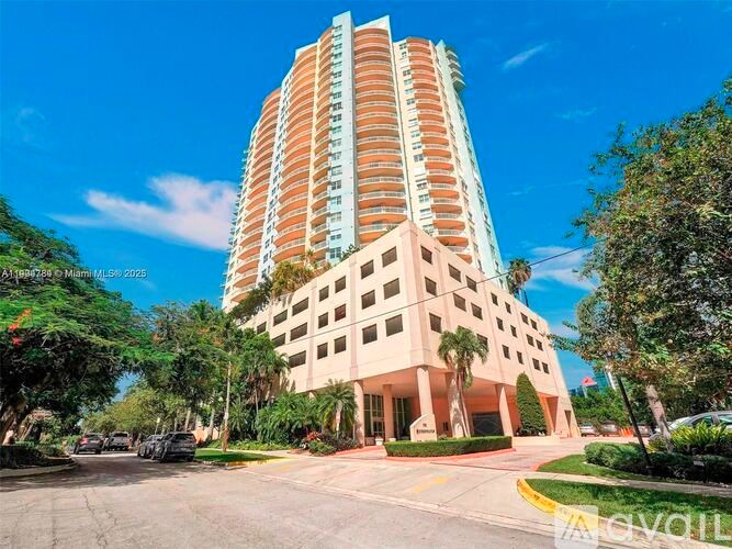 A tall building with a beige facade stands in front of a clear blue sky.