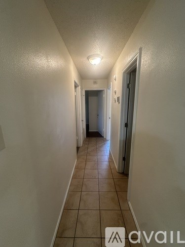 A long hallway with tiled floors and white walls.