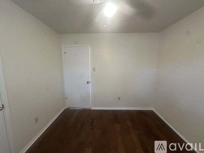 A room with a white door and wooden floor.