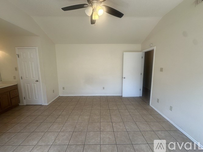 A room with a ceiling fan and tile flooring.