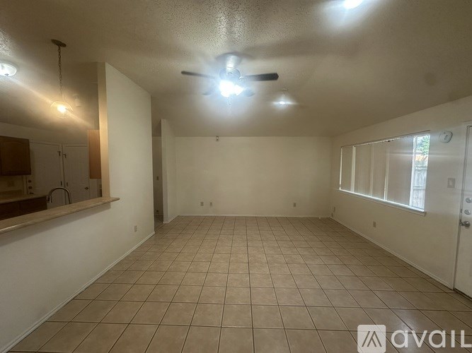 A spacious room with tiled flooring and a ceiling fan.