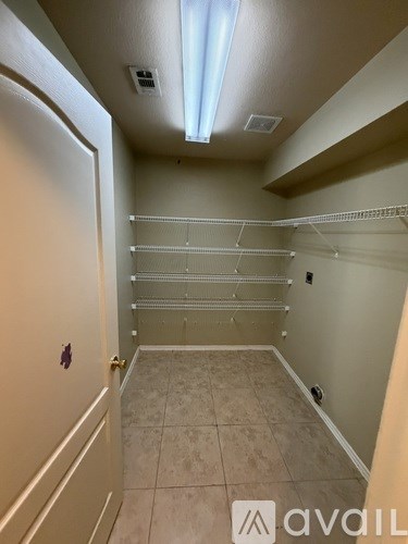 A large empty walk-in closet with shelves and a door.