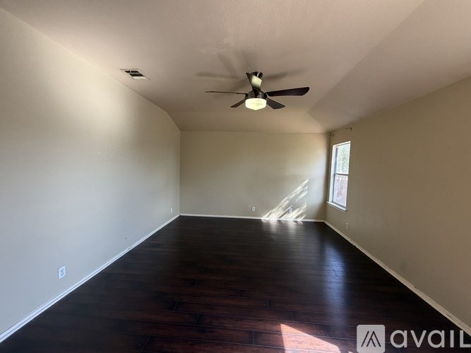 A room with a ceiling fan and wooden flooring.