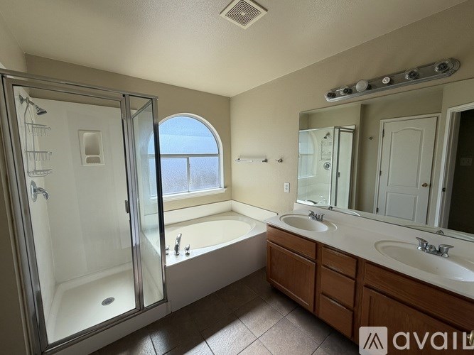 A bathroom with a large mirror, a bathtub with a shower, and a window.