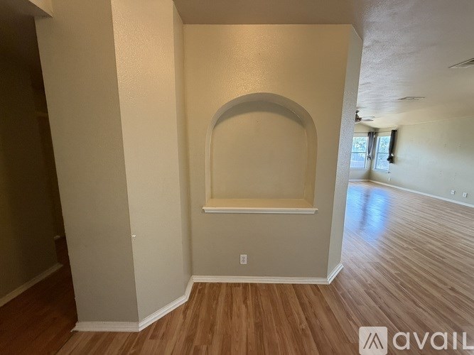 A room with wooden floors and a large arched window.