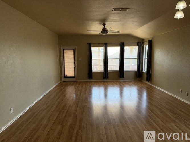 A spacious room with wooden floors and a ceiling fan.