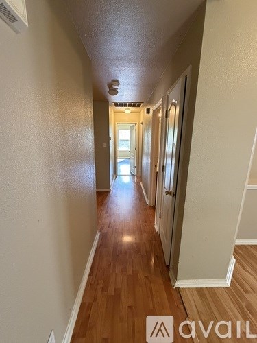 A long hallway with wood floors and white walls.