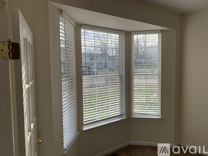 A room with a window covered by white blinds.