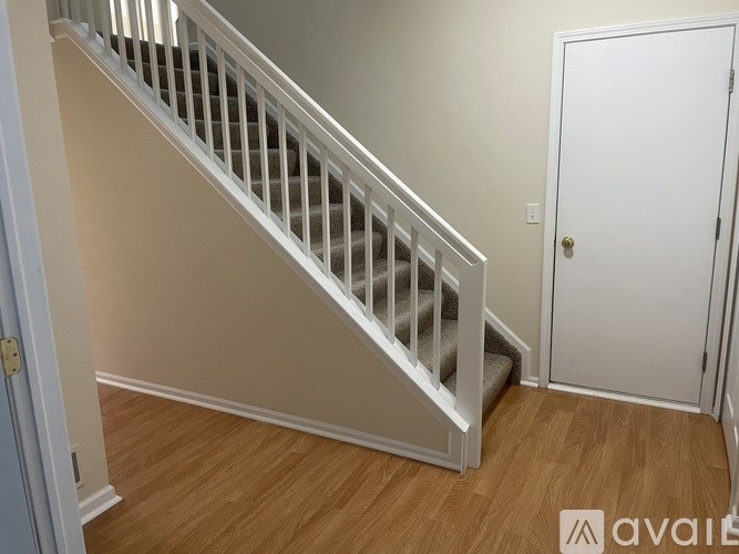 A staircase with white railings and a white door on the right.