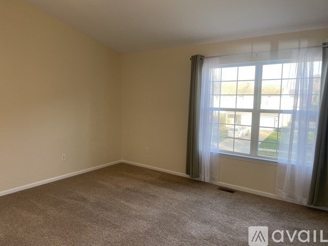 A room with a carpeted floor and a window with curtains.