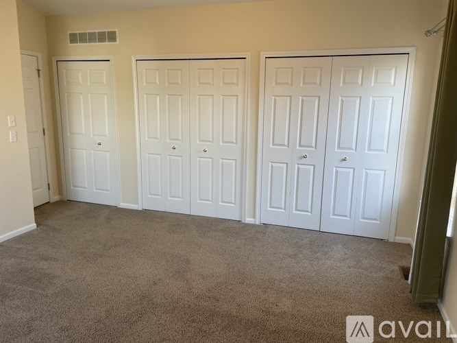 A room with white doors and carpeted floor.