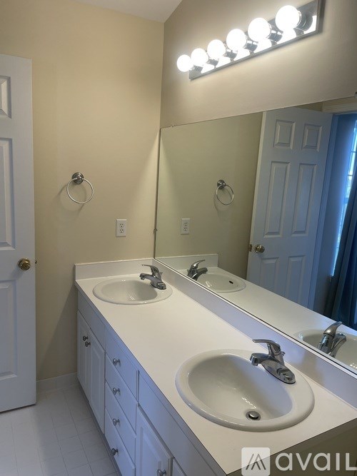 A bathroom with two sinks and a mirror with lights above it.