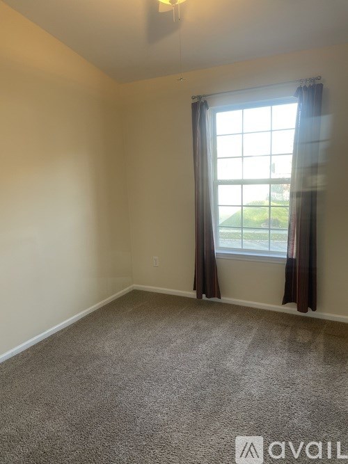 A room with a carpeted floor and a window with curtains.