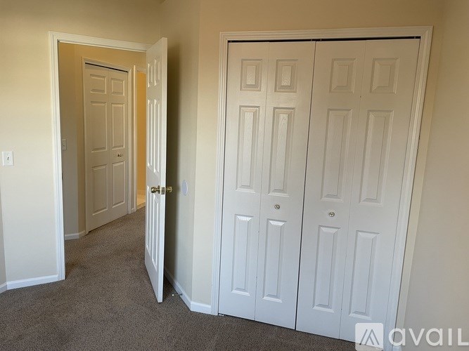 A room with a carpeted floor and two white doors.