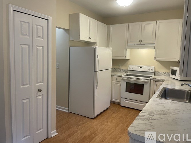 A kitchen with white appliances and cabinets.