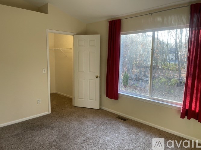 A room with a white door and a window with red curtains.