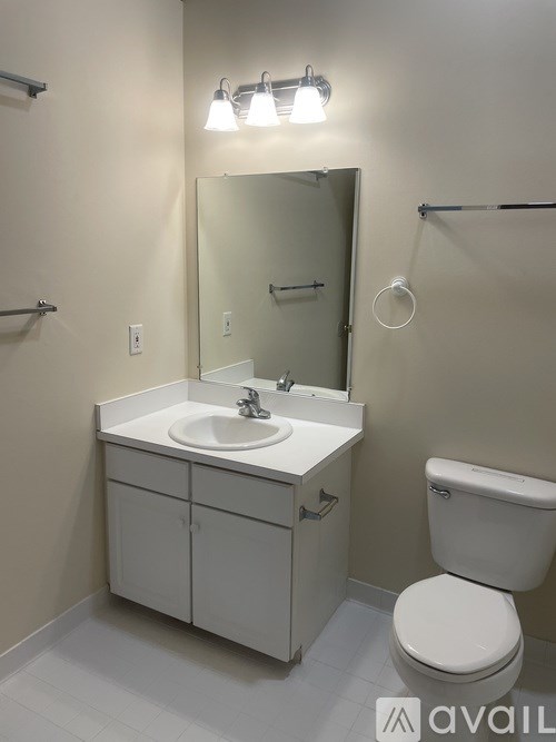 A white bathroom with a toilet, sink, and mirror.