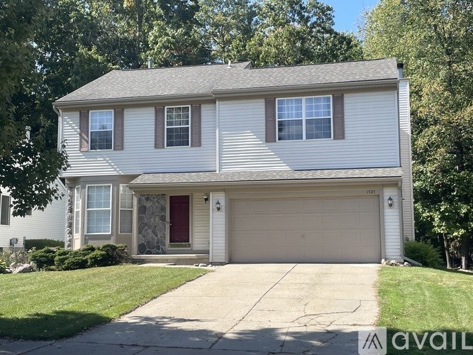 A two-story house with a red door and garage door.