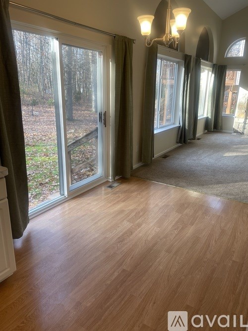 A room with wooden floors and a large window with a view of trees.