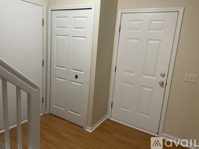 A white door with a black handle is in a room with wooden floors.