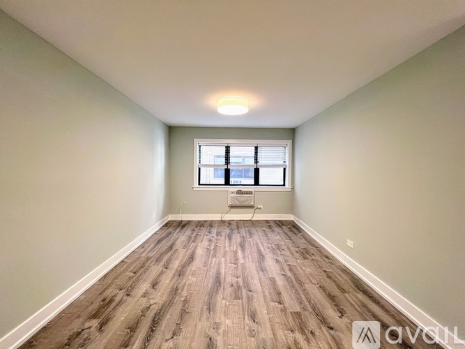 A room with wooden flooring and a window with blinds.